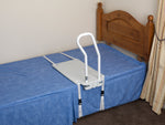 This image shows the bed rail attached using straps to a blue divan style bed with a wooden head frame. The room is cream and the floor is brown. 