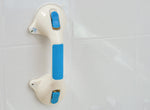 This image shows the white and blue suction grab bar attached to a white tiled bathroom wall. 
