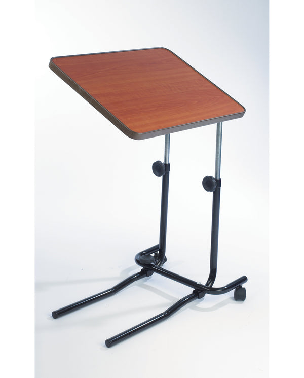 Image shows a brown desk with silver and black stand on one side, against a white background. The product has two black wheels and curved edges to the desk. 