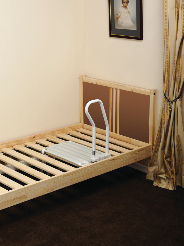 This image shows the product attached to a slatted wooden bed frame, without a mattress in place to demonstrate the set up. The room is cream with golden curtains and a photo of a child above the bed. 