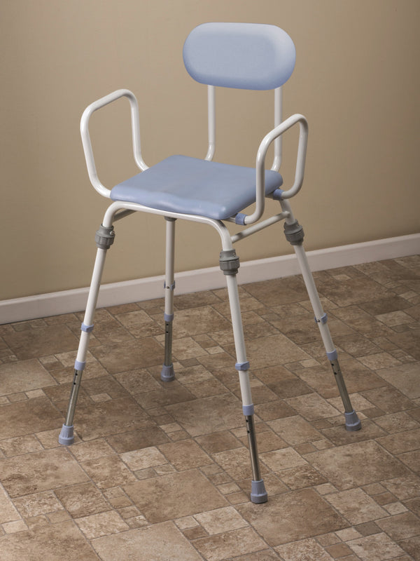 This image shows the product on brown tiled floor against a cream wall. The pale blue cushion seat and back support sits on a white frame with grey legs. 