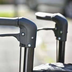This image shows the two black handles of the Rollator and breaks, against a blurred out background. 