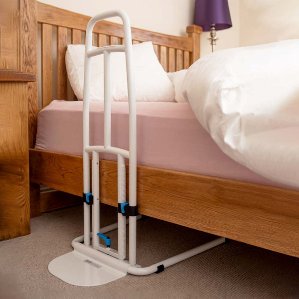 This image shows the white bed rail fitted to a wooden bed and secured on the ground under the bed. 