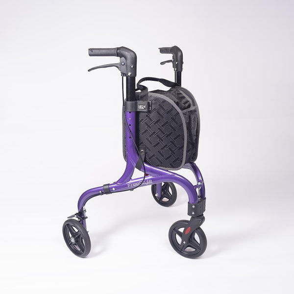 mage shows three wheeled purple and black rollator with black storage bag between the handles. The small black wheels, and black handles and break system are also clear, against the white background.